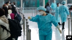 身穿防護服的香港機場工作人員指引抵港旅客排隊前往防疫隔離酒店。（2022年4月1日）