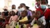 Women holding babies take their places on wooden benches at a clinic in Harare, Zimbabwe, Thursday, Sept. 15, 2022. 