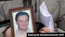 RUSSIA -- A portrait of lawyer Sergei Magnitsky, who died in jail, is held by his mother Nataliya Magnitskaya, as she speaks during an interview with the AP in Moscow, November 30, 2009
