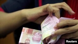 FILE: Seorang karyawan menghitung uang kertas rupiah Indonesia di kantor penukaran mata uang di Jakarta, 23 Oktober 2018. (REUTERS/Beawiharta)