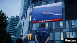 北京市民在觀看街頭電子屏幕上官媒央視播放的中國軍隊在台灣附近舉行實彈軍演的報導。 （2022年8月4日）