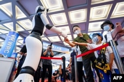 北京舉行的2022世界機器人大會上一個機器人與參觀者握手。（2022年8月18日）