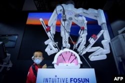 北京舉行的2022世界機器人大會上一名兒童在註視一個可以進行外科手術的機械手。（2022年8月18日）