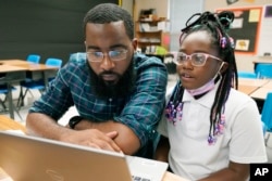Ryan Johnson, a fifth-grade teacher at Pecan Park Elementary School, left, checks to see what homework his daughter, Rylei, is bringing home, as they prepare to leave Johnson's classroom in Jackson, Miss., Tuesday, Sept. 6, 2022.