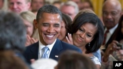 Arhiva - Predsednik Barak Obama i prva dama Mišel Obama aplaudiraju tokom ceremonije otkrivanja portreta bivšeg predsednika Džordža V. Buša i bivše prve dame Lore Buš, 31. maja 2012. u Beloj kući u Vašingtonu.