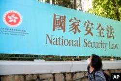 香港一名婦女走過街頭的國安法宣傳牌。 （2020年6月30日）