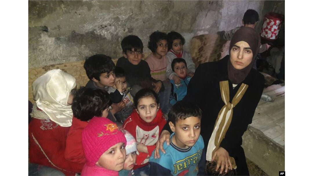 This March 11, 2018 photo, provided by Deana Lynn, from Detroit, Michigan, shows her, with her kids and other Syrian children at a shelter where they hide from Russian and Syrian government forces airstrikes, in eastern Ghouta, a suburb of the Syrian capital Damascus.