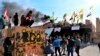 Pro-Iranian militiamen and their supporters set a fire during a sit-in in front of the U.S. embassy in Baghdad, Iraq, Wednesday, Jan. 1, 2020.