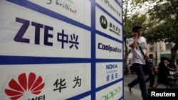 一名中国男子从武汉街头有着华为和中兴标徽的广告牌前走过。（资料照片）