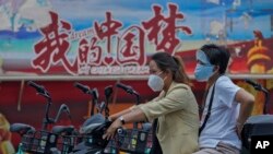 騎著電動車的中國女子駛過中國夢的宣傳畫。 （2022年6月20日）