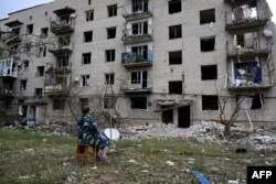Žena sedi ispred svoje četvorospratne, koja je delimično uništena u ruskom raketnom napadu, u Časiv Jaru, region Donjecka, istočna Ukrajina, 10. jula 2022.