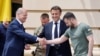 Ukrainian President Volodymyr Zelensky (R) shakes hands with Germany's Chancellor Olaf Scholz (L) next to France's President Emmanuel Macron prior to their meeting in Kyiv, on June 16, 2022.