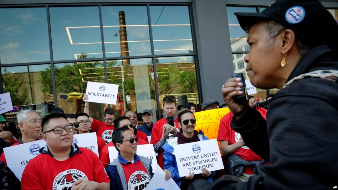 Michelle Dottin, a driver and stewart with the Independent Drivers Union Guild, speaks at a rally outside Uber and Lyft offices, calling for "fair pay for all drivers," May 8, 2019, in New York. 