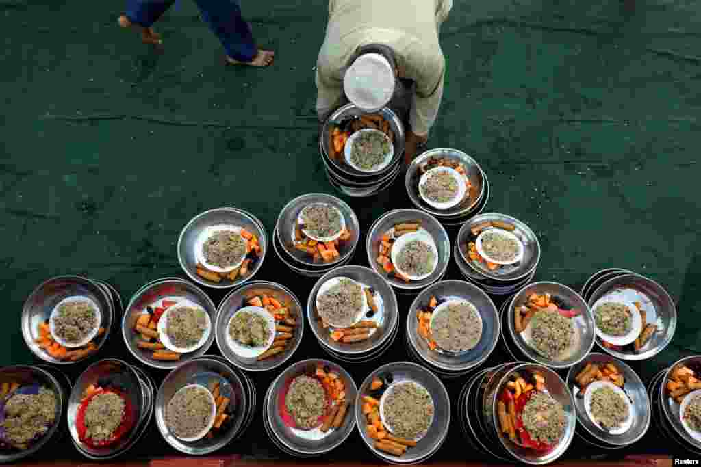 Pakistan’ın Karaçi kentinde bulunan bir camiide iftarını açan cemaate bir gönüllü yiyecek dağıtıyor.