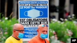 Ljudi nose zaštitne maske prlazeći pored obaveštenja o obaveznom nošenju maski i na ulici, u Bajonu, jugozapadna Francuska, 28. jula 2021.