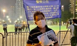 警方六四32周年纪念日引公安条例，围封原定支联会六四烛光集会场地维园足球场及草坪，有市民在警方警告横额前手持悼念六四的LED蜡烛 (美国之音/汤惠芸)