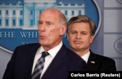 U.S. -- FBI Director Christopher Wray listens as U.S. Director of National Intelligence Dan Coats participates in a briefing on election security in the White House press briefing room at the White House in Washington, August 2, 2018.