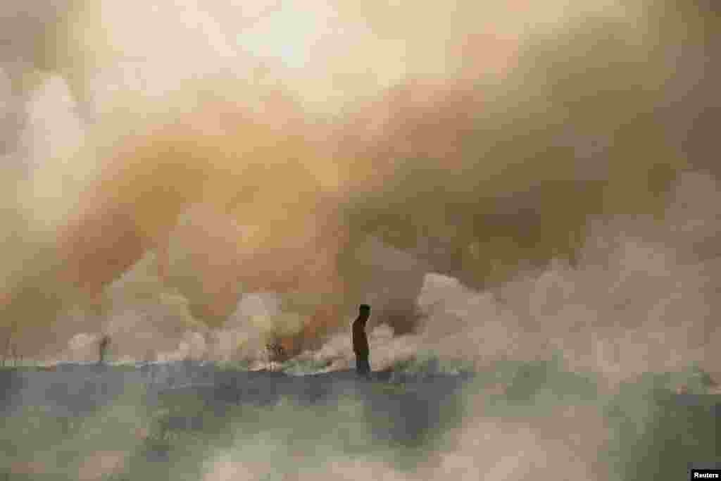 A disaster management officer walks toward a brush fire as other firefighters (not pictured) attempt to extinguish it near Palembang, South Sumatra, Indonesia in this photo taken by Antara Foto.