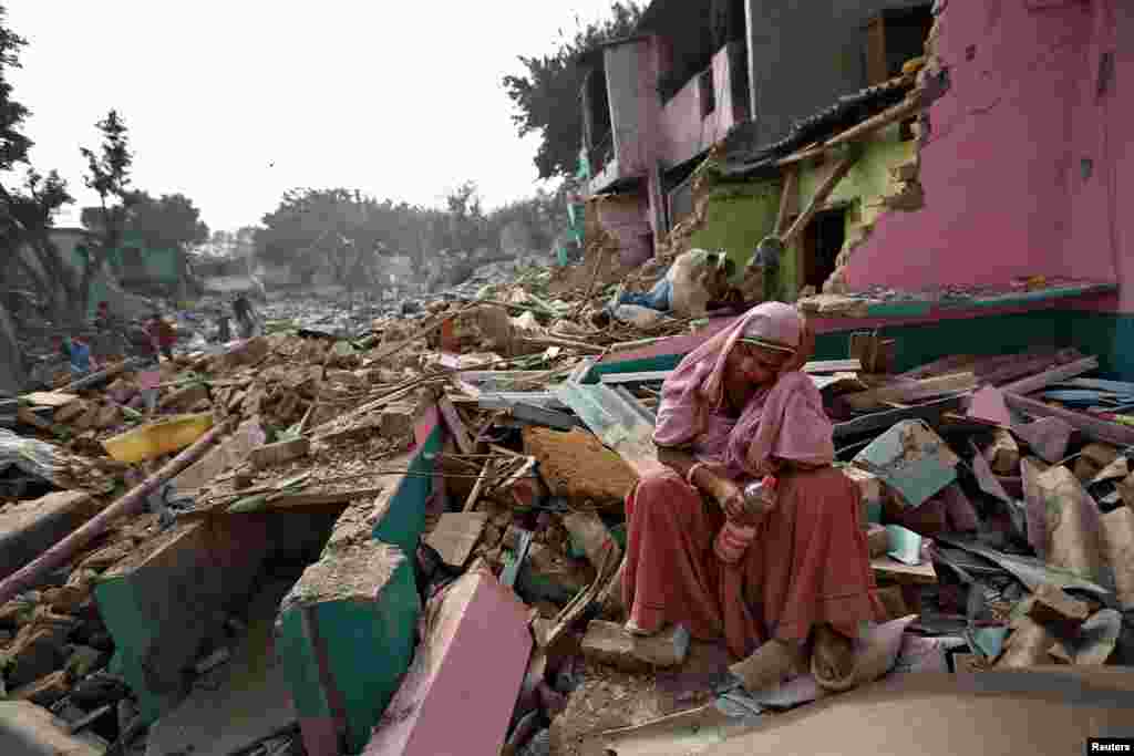 A woman reacts after her home was razed by local authorities in a bid to relocate the residents of a Delhi slum, India.