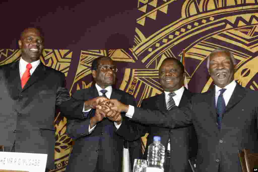Officials join hands at the signing of the power-sharing deal in Harare, Zimbabwe, Sept, 15, 2008. From left: Arthur Mutmbara, deputy prime minster; Robert Mugabe, president; Morgan Tsvangirai, prime minster; and Thabo Mbeki, South Africa's president.