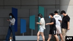 北京字節跳動總部大樓旁幾個青年邊走路邊看手機。 （2020年7月6日）