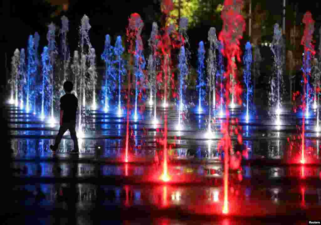 A child walks through the color lit fountain in Nice, France, Sept. 20, 2017.