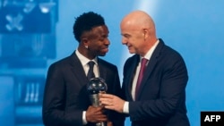 Vini Jr. recebe o prémio The Best das mãos do presidente da FIFA, Gianni Infantino, em Doha, Qatar, 17 dezembro 2024. (Photo by Karim JAAFAR / AFP)