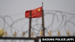 資料照：中國新疆喀什南部一處住宅區牆上的鐵絲網與中國國旗。 （2019年6月4日）