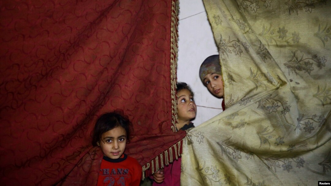 Children stand near curtains in a shelter in the besieged town of Douma, eastern Ghouta, in Damascus, Syria, March 11, 2018. 
