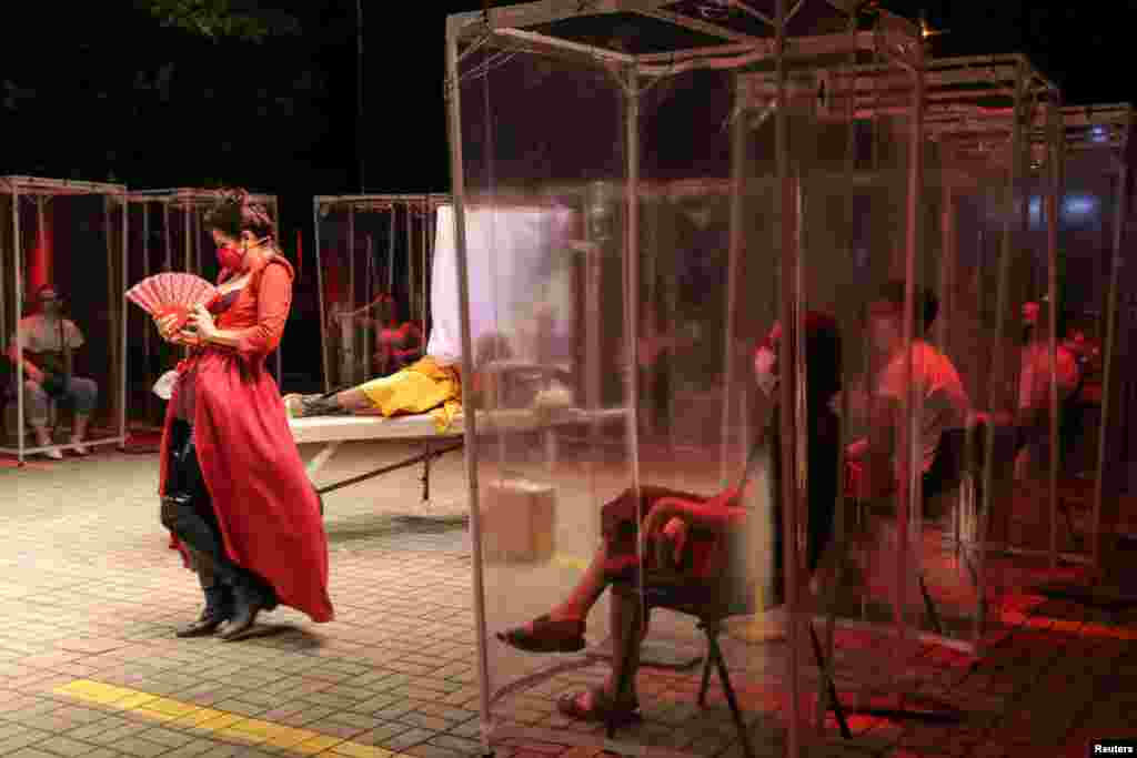 Spectators keep social distance inside individual plastic cabins as they watch the play "Volpone Protocol" staged by Bendita Trupe during the coronavirus outbreak, in Sao Paulo, Brazil, Oct. 28, 2020.