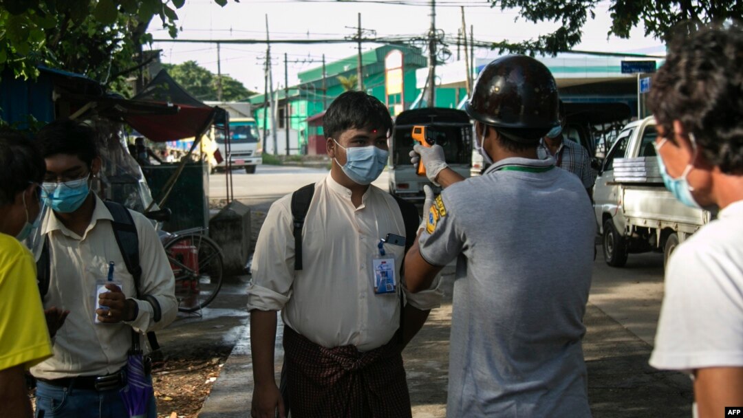 အဝင်အထွက်ပိတ်ဆို့ထားသည့် ရန်ကုန်မြို့ လမ်းသွယ်တခုတွင် ကိုယ်အပူချိန် တိုင်းတာပေးနေသည့် လုပ်အားပေးများ။ (စက်တင်ဘာလ ၁၁၊ ၂၀၂၀)