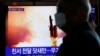 Čovek sa maskom, kojom se štiti od koronavirusa,, posmatra snimak lansiranja neidentifikovane severnokorejske rakete, u Seninu, Južna Koreja, 9. marta 2020.(Foto: Reuters)