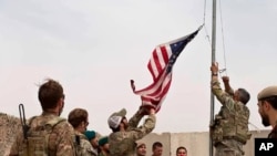 A U.S. flag is lowered as American and Afghan soldiers attend a handover ceremony from the U.S. Army to the Afghan National Army, at Camp Anthonic, in Helmand province, southern Afghanistan, May 2, 2021.