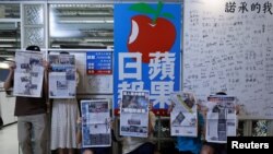 香港苹果日报员工手持最后一起报刊在公司标志旁留影。（2021年6月24日）