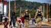 FILE - U.S. Military Police walk past Afghan refugees at the Fort McCoy U.S. Army base, Sept. 30, 2021, in Wisconsin.