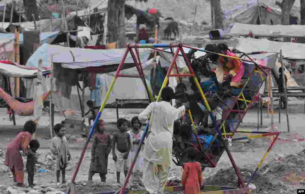 Pakistani children ride on a swing near their makeshift tents in a slum area of Lahore.