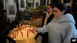 FILE - A Syrian Christian woman lights a candle during the first Sunday Mass since Syrian President Bashar al-Assad's ouster, at Mariamiya Orthodox Church in Old Damascus, Syria, Dec. 15, 2024.