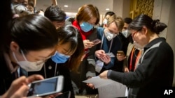 FILE - Journalists wearing face masks look at a government statement prior to a press conference about the coronavirus outbreak, in Beijing, China, Jan. 26, 2020.