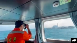 在這張從台灣海巡署發布的視頻截圖中，一名海巡署成員正在監視一艘中國海警船，該船於2024 年10 月14 日經過台灣馬祖群島附近海岸。