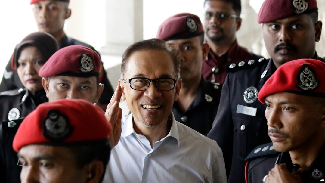 FILE - Deputy Prime Minister and opposition leader Anwar Ibrahim, center, smiles as he arrive at court house in Kuala Lumpur, Malaysia, June 13, 2017.