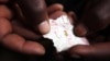 FILE - A Congolese mineral trader holds a piece of paper containing nuggets of gold in a mud hut at Numbi in eastern Congo.