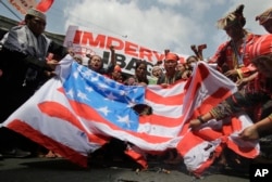 Philippines US: Filipino tribal groups and activists shout slogans as they burn a mock U.S. flag near the Malacanang presidential palace in Manila, Philippines, Friday, Oct. 21, 2016.