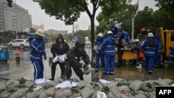 A team puts sandbags next to Yuyao river in Ningbo, eastern China's Zhejiang province on July 25, 2021, as Typhoon In-Fa lashes the eastern coast of China. (Photo by Hector RETAMAL / AFP)