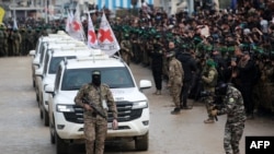 Anggota pasukan Hamas berjalan di depan kendaraan Palang Merah saat mereka tiba di kamp Nuseirat di Jalur Gaza untuk menerima tiga sandera Israel dalam proses pertukaran sandera dan tahanan antara Hamas dan Israel pada 22 Februari 2025. (Foto: AFP/Bashar Taleb)