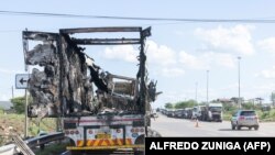 Visão geral de um camião queimado enquanto outros camiões fazem fila para tentar chegar ao posto de fronteira de Ressano Garcia, entre Moçambique e África do Sul, em 13 de novembro de 2024