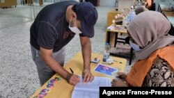 FILE - A Libyan man registers to vote inside a polling station in Tripoli, Nov. 8, 2021. 