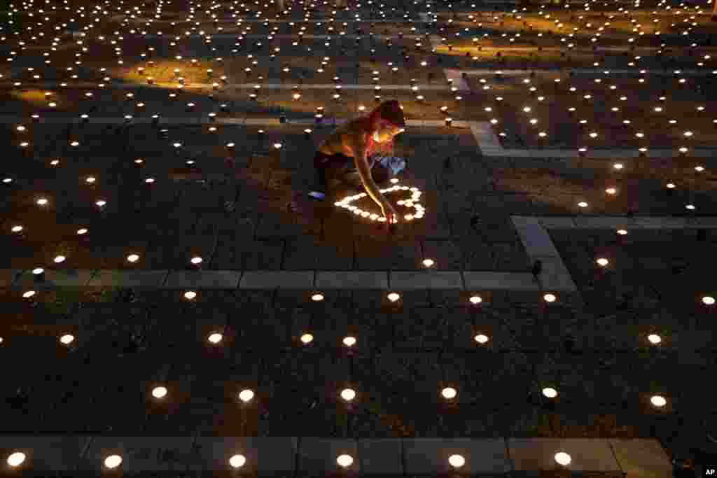A woman lights memorial candles on the 25th anniversary of the assassination of Israeli Prime Minister Yitzhak Rabin, at Rabin Square, Tel Aviv, Israel.