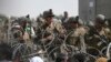 Tentara AS berjaga di balik kawat berduri saat warga Afghanistan duduk di pinggir jalan dekat bagian militer bandara di Kabul pada 20 Agustus 2021. (Foto: AFP/Wakil Kohsar)