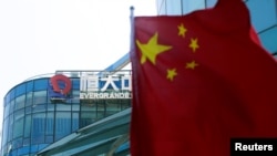 A Chinese flag flutters in front of the logo of China Evergrande Group seen on the Evergrande Center in Shanghai, China September 22, 2021. REUTERS/Aly Song