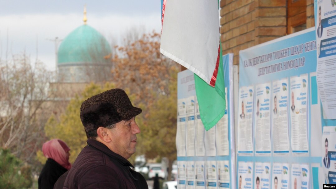 A man reads election candidates posters during parliamentary election in Tashkent, Uzbekistan, Dec. 22, 2019.